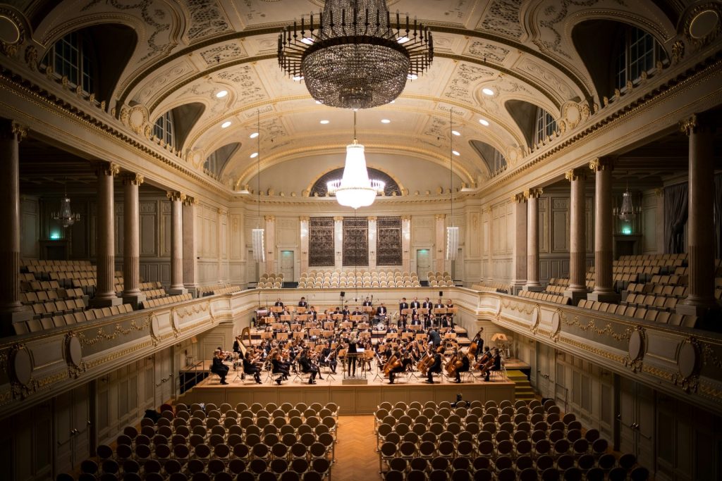 music group performing on stage with empty audience seats